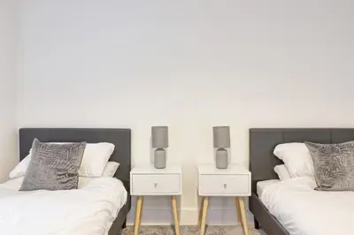 two beds with white sheets and two nightstands with pillows at 3 Bed, Sleeps 6, Wifi, Free Parking in Writtle