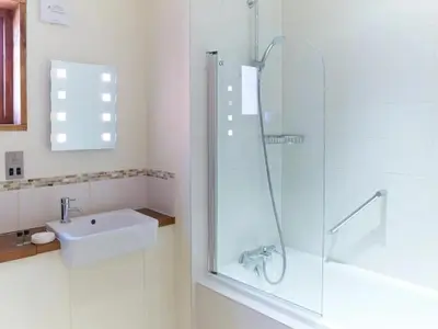 a white bathroom with a shower and a sink at Thorpe Forest Cabins - Forest Holidays in Thetford