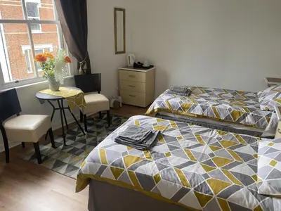 a bedroom with two beds and a table with a vase of flowers at Ipswich Inn in Ipswich
