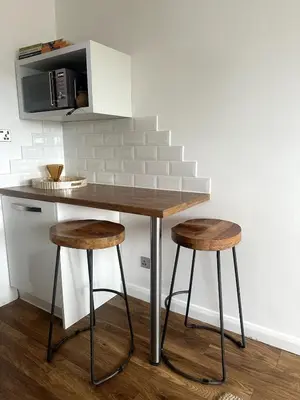 a kitchen counter with two stools and a microwave at Flat-on-Sea in Southend-on-Sea