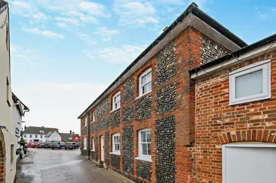 a red brick building with white windows on a street at 2 Bed in Lavenham oc-f30054 in Lavenham