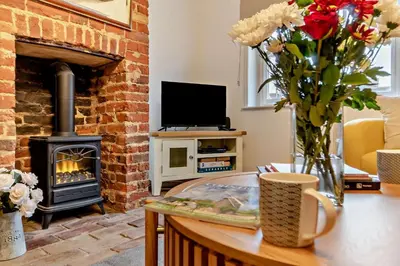 a living room with a fireplace and a table with flowers at 2 Bed in Lavenham oc-s30055 in Lavenham
