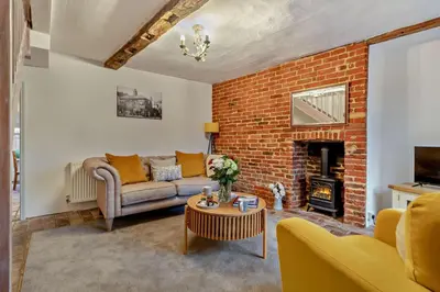 a living room with a couch and a brick wall at 2 Bed in Lavenham oc-s30055 in Lavenham