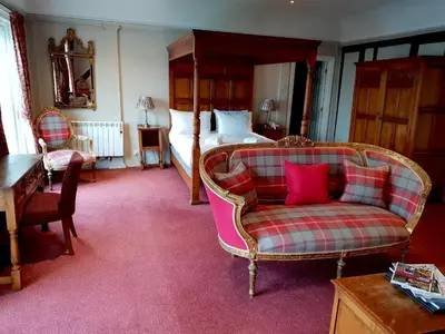 a bedroom with a bed and a couch and a chair at The Crown Hotel in Framlingham
