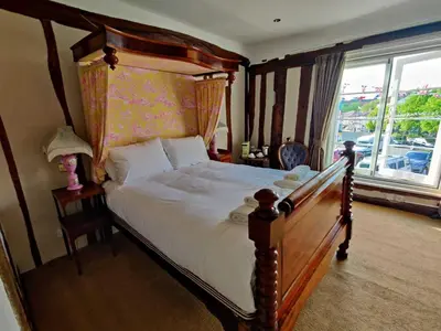 a bedroom with a bed with a wooden frame and a window at The Crown Hotel in Framlingham