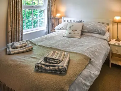 a bedroom with a bed with towels and a window at Eva's Cottage in Wenhaston