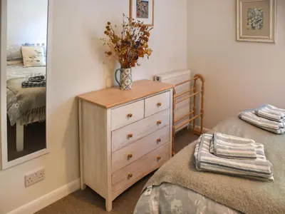 a bedroom with a dresser and a bed with a mirror at Eva's Cottage in Wenhaston