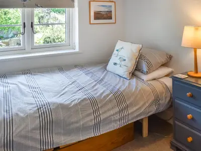 a bedroom with a bed with a pillow and a window at Eva's Cottage in Wenhaston