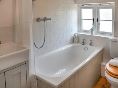 a white bathroom with a tub and a toilet at Eva's Cottage in Wenhaston