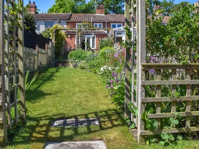 a garden with a wooden fence and flowers at Eva's Cottage in Wenhaston