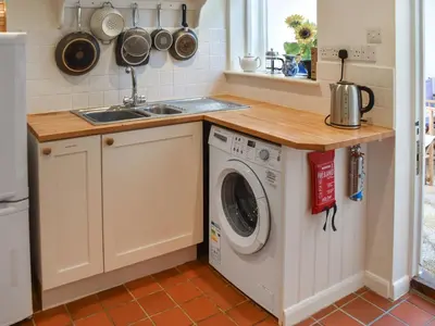 a kitchen with a washing machine and a sink at Eva's Cottage in Wenhaston