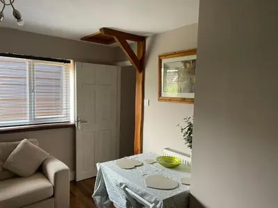 a living room with a table and a couch at Barn conversion Corner Annexe in Earls Colne