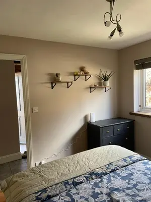 a bedroom with a bed and shelves on the wall at Barn conversion Corner Annexe in Earls Colne