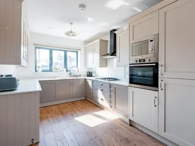 a kitchen with white cabinets and a wooden floor at Hawkwell Retreat 5 Bedroom home Hockley - Pass the Keys in Hawkwell