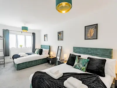 a bedroom with two beds and a living room at Hawkwell Retreat 5 Bedroom home Hockley - Pass the Keys in Hawkwell