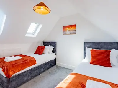 two beds in a room with white walls and red pillows at Hawkwell Retreat 5 Bedroom home Hockley - Pass the Keys in Hawkwell