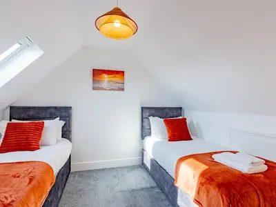 two beds in a room with white walls and red pillows at Hawkwell Retreat 5 Bedroom home Hockley - Pass the Keys in Hawkwell