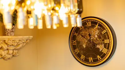 a clock hanging on a wall next to a chandelier at Paradise Penthouse in Downham Market