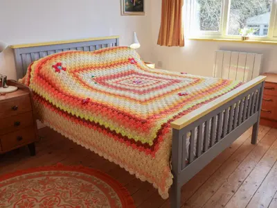 a bed with a crochet blanket on it in a bedroom at The Orchard Close Art House in Great Livermere