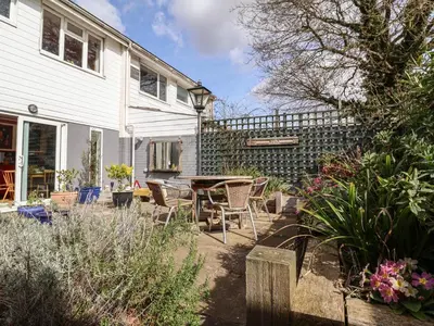 a patio with chairs and a table in front of a house at The Orchard Close Art House in Great Livermere