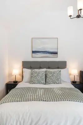 a bedroom with a large bed with two lamps at Chandini Villa in High Wych in Sawbridgeworth
