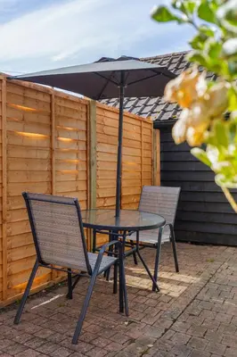 a table and chairs with an umbrella on a patio at Chandini Villa in High Wych in Sawbridgeworth