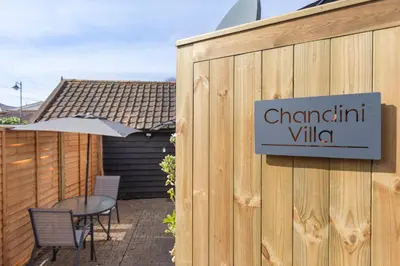 a sign on the side of a wooden fence with a table at Chandini Villa in High Wych in Sawbridgeworth