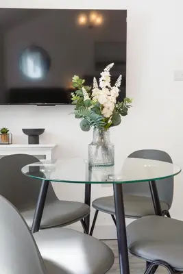 a glass table with a vase of flowers on it at Chandini Villa in High Wych in Sawbridgeworth