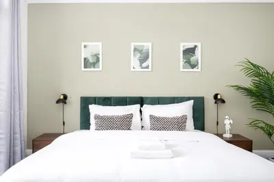 a bedroom with a large white bed with four pictures on the wall at Ocean Breeze in Thorpe Bay