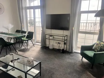 a living room with a tv and a table and chairs at Ocean Breeze in Thorpe Bay