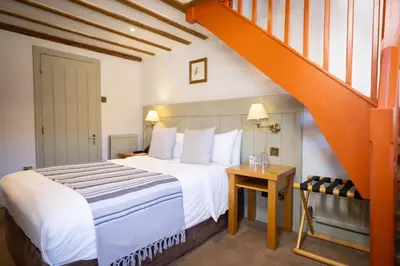 a bedroom with a white bed and an orange staircase at Tewinbury Farm Hotel in Tewin