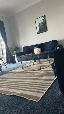 a living room with a blue couch and a rug at Seaside Escape in Thorpe Bay
