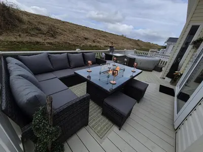 a patio with a couch and a table on a deck at The Blue Lagoon 2 bedroom lodge with hot tub in Walton-on-the-Naze