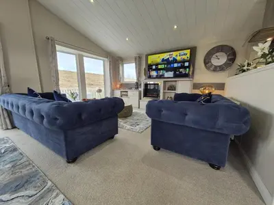 a living room with two blue couches and a television at The Blue Lagoon 2 bedroom lodge with hot tub in Walton-on-the-Naze