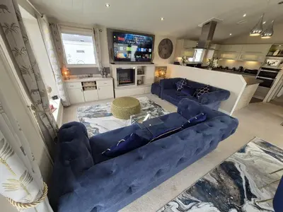 a living room with blue couches and a tv at The Blue Lagoon 2 bedroom lodge with hot tub in Walton-on-the-Naze