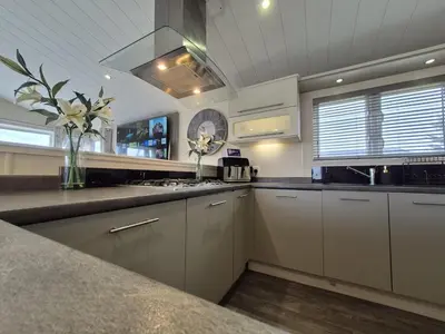 a kitchen with white cabinets and a vase of flowers at The Blue Lagoon 2 bedroom lodge with hot tub in Walton-on-the-Naze