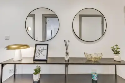 a table with two mirrors on a white wall at Stylish stay Ware town with parking in Ware