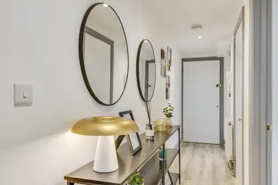 a hallway with two mirrors and a table with a gold lamp at Stylish stay Ware town with parking in Ware