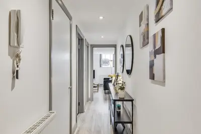 a hallway with white walls and a table and mirrors at Stylish stay Ware town with parking in Ware