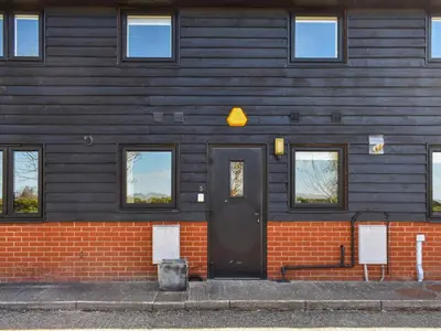 a house with a black door and a brick wall at Periwinkle No5 - Uk49249 in Althorne