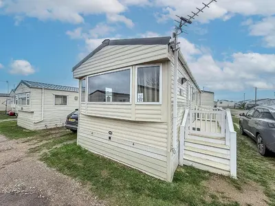 a small white house with a large window at 6 Berth Caravan With Side Decking At Suffolk Sands Holiday Park Ref 45054C in Felixstowe