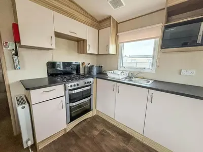 a kitchen with white cabinets and a stove top oven at 6 Berth Caravan With Side Decking At Suffolk Sands Holiday Park Ref 45054C in Felixstowe