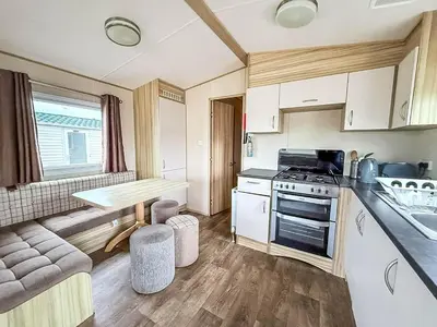 a small kitchen with a table and a stove at 6 Berth Caravan With Side Decking At Suffolk Sands Holiday Park Ref 45054C in Felixstowe