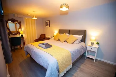 a bedroom with a large bed with a yellow blanket at The Serene Suite Brandon in Brandon