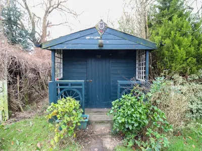 a blue outhouse in the middle of a garden at Crown Farm in Wisbech