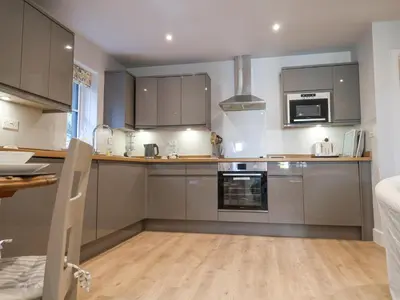 a kitchen with stainless steel appliances and wooden floors at Bradley's Barn in Colchester