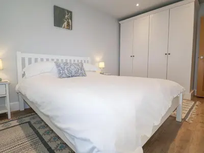 a bedroom with a large white bed with white cabinets at Bradley's Barn in Colchester