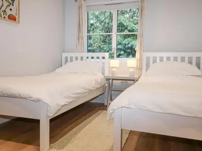 two beds in a bedroom with a table and a window at Bradley's Barn in Colchester