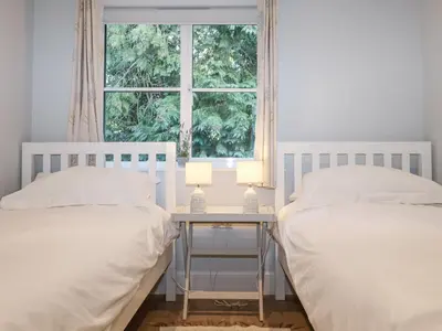 a bedroom with two beds and a table with two lamps at Bradley's Barn in Colchester