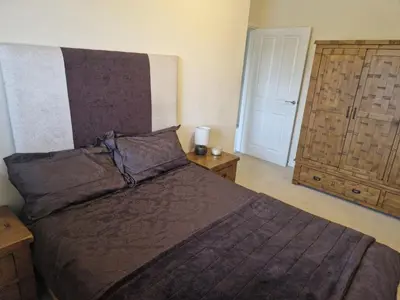 a bedroom with a bed with a brown blanket and a door at Lovely and Cosy Double Room in Havering atte Bower